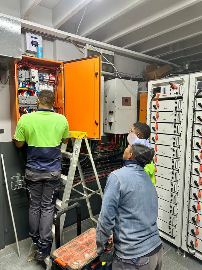 DigiGo technicians commissioning a commercial solar plant room with battery racks